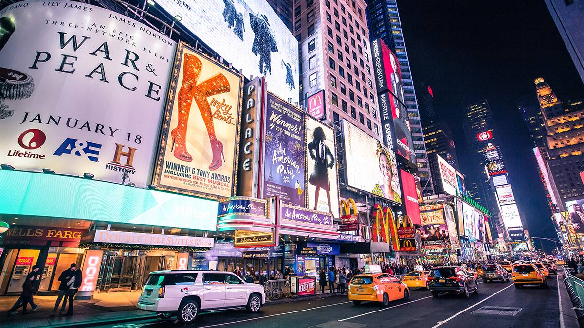 Wide shot of Broadway at night with lots of traffic and lights in NYC, New York, USA